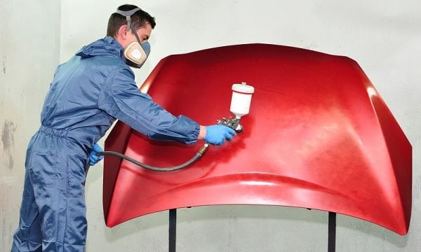 Application de peinture rouge sur métal avec un pistolet pulvérisateur
